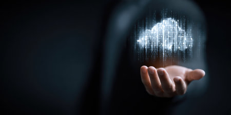 A hand holds a glowing cloud symbol, representing cloud computing and data storage. The image features a dark background with digital light effects. This visual could be used in technology presentations, illustrating concepts of network, connectivity, or data management. It suggests the availability and accessibility of digital information.の素材