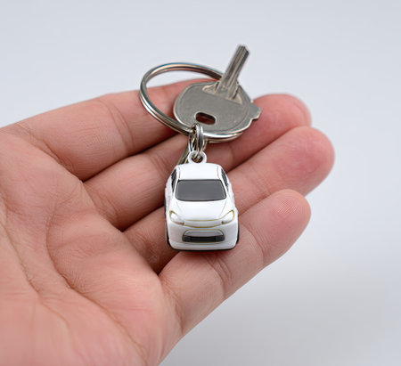 Car key with keychain in hand isolated on a white background.の素材