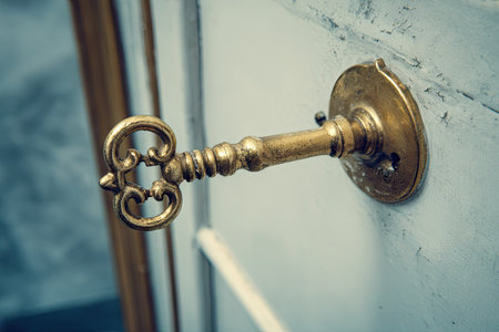 Vintage brass key on a white wall. Selective focus.の素材