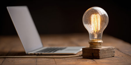 Laptop and light bulb on a wooden table. Business concept.の素材