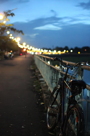 Bicycle on the bridge in the evening with lights on background.の素材