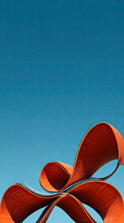 An abstract, metallic red sculpture is depicted against a vivid, cloudless blue sky. The composition emphasizes the curves and form of the artwork under bright daylight. Its clean lines and bold color suggest potential use in various design projects or visual content, suitable for advertising and editorial purposes.の素材