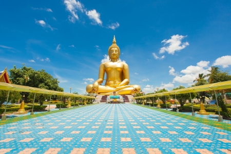 Golden Buddha statue on Asian temple building with blue sky and cloudscape background の写真素材