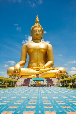 Golden Buddha statue on Asian temple building with blue sky and cloudscape background の写真素材