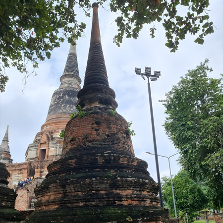 A serene view of ancient stupas in an Ayutthaya temple, showcasing timeless Thai architecture against a peaceful natural backdrop. The weathered brick, graceful forms and historic.の写真素材