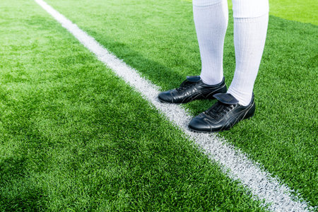 Soccer player ready to play at white line in soccer field.