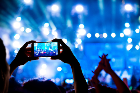 silhouette hands of a man use smart phone enjoying the concertの写真素材