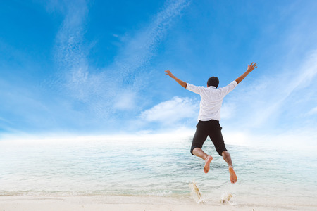 Happiness of businessman jumping relax on beautiful sea beach at vacationの写真素材