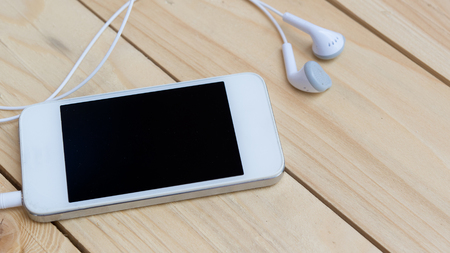 Smart phone and earphones on a wood background is a player music, Top view, Listen to music concept.の写真素材