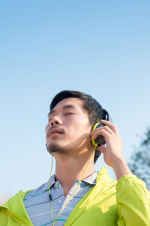 man listening music headphones from smartphone at natural outdoorの写真素材