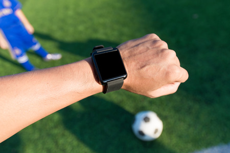 Close-up hands of man using his smart watch exercise in soccer fieldの写真素材