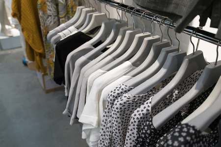 Clothes hang on a shelf in storeの写真素材