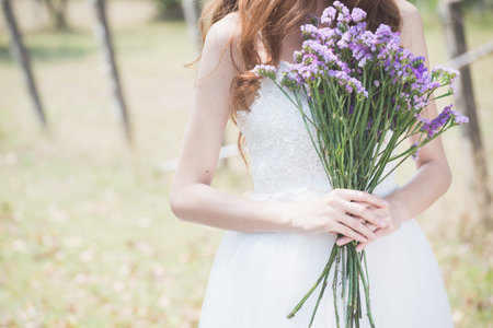 woman in white dress and flower on her hands at parkの写真素材