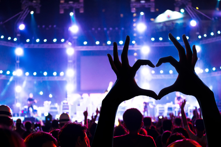 Concert crowd raising heart shaped hands at concert, loving the artist and the festival. Music concertの写真素材