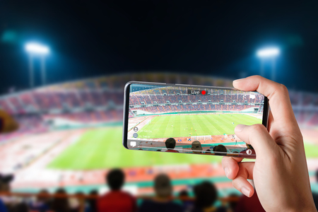 People hands use smartphones record soccer competition match in football stadium live streaming video on internet to social media comment chat to Friendの写真素材