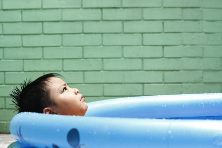 Boy In A Mini Swimming Pool   A little boy cools off in an inflatable mini swimming pool to beat the summer heat の写真素材