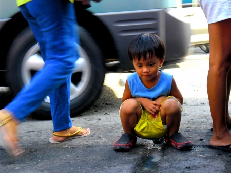 An asian boy rests in the middle of a sidewalkの素材