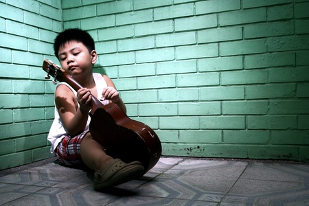 Young asian kid playing a yukeleleの素材