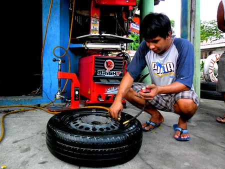 Worker fixing a car tireの素材