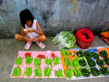 Young asian girl selling vegetables in a market in cainta, rizal, philippinesの素材