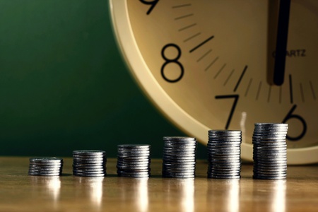 Stacks or piles of coins and a clockの素材