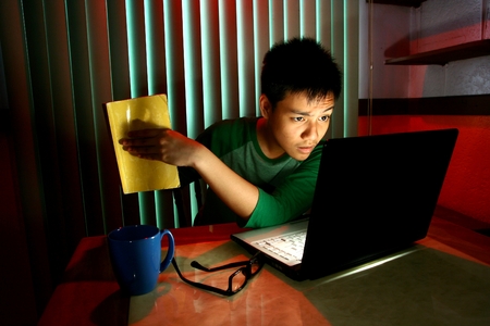 Young Teen holding a book in front of a laptop computerの写真素材