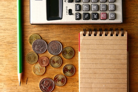 Coins, pencil, notebook and calculator on a tableの素材