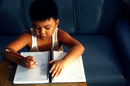 Young boy writing on a notebookの素材