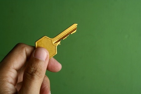 Hand holding a golden keyの素材