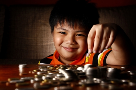 Photo of a young boy stacking or piling coinsの写真素材