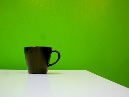 coffee mug on a table against a green wallの写真素材