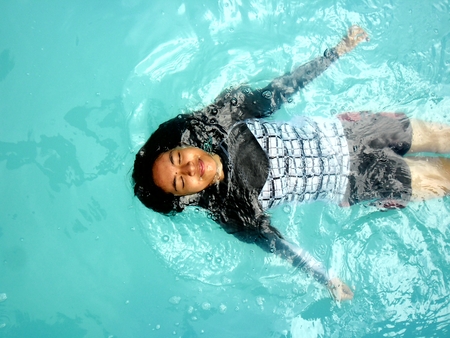 Photo of a Teenage girl swimming backstroke in a poolの写真素材