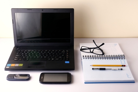 Laptop computer cellphone smartphone notebook pen pencil and eyeglassesの写真素材