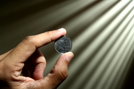 Hand holding a coinの写真素材