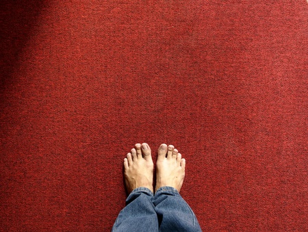 Pair of feet standing on a red carpetの素材