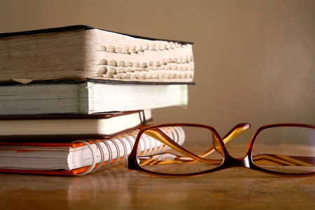 Eyeglasses and pile of booksの写真素材