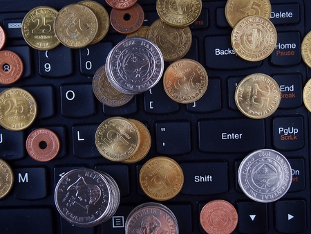 Coins on the keyboard of a laptop computerの写真素材