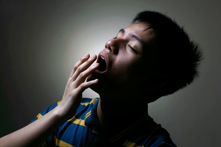 Male teenager yawningの写真素材