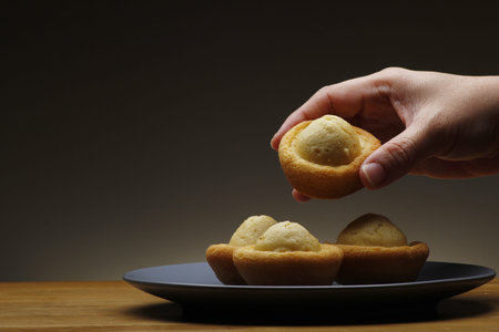 Hand getting a freshly baked Filipino muffin known as kabayan from a pile