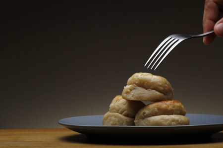 Hand holding a fork about to poke a freshly baked Filipino-Chinese sweet bread called hopya