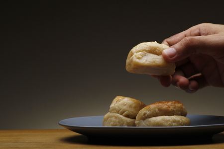 Hand getting a freshly baked Filipino-Chinese sweet bread called "hopya" from a pileの写真素材