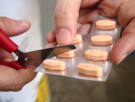 Person holding a scissors cuts a tablet from a pack of medicine'OLYMPUS DIGITAL CAMERAの写真素材
