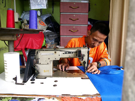 A tailor sewing a dress inside a tailoring shopの素材