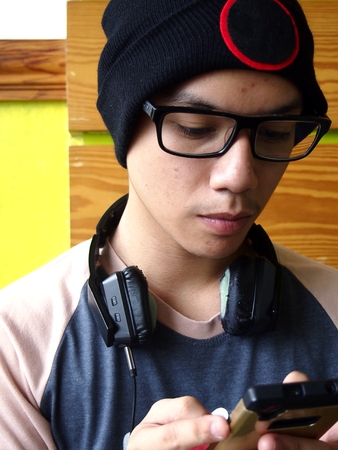 Hip male teenager using a smartphoneの写真素材