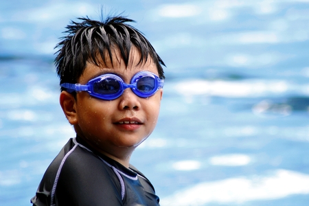 Young boy with swimming goggles in a swimming pool.の写真素材