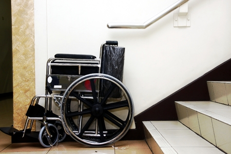 Wheelchair parked at the bottom of a set of staircase.の写真素材