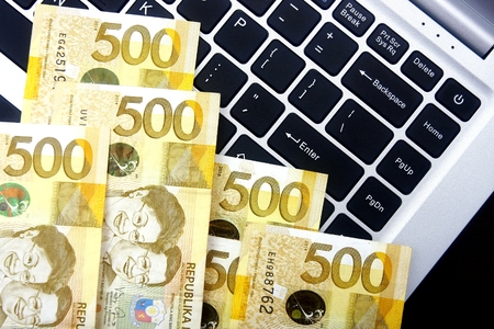 Philippine peso bills on a laptop computer keyboard.の写真素材