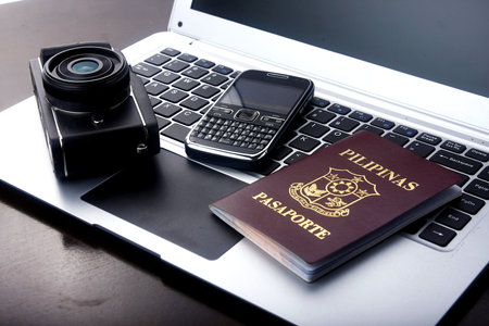 Camera, passport and cellphone on a laptop computer keyboard.