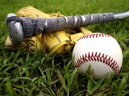 Photo of a baseball gloves, baseball and a baseball bat on the grassの写真素材