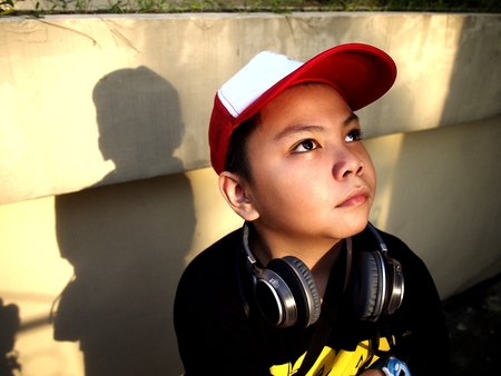Photo of a young boy wearing a hat and headphones on his neckの写真素材